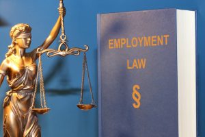 Symbolic image: Employment law reference book paired with a statue of Lady Justice (Justitia).
