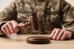 Law concept. Man in military uniform with gavel at wooden table.