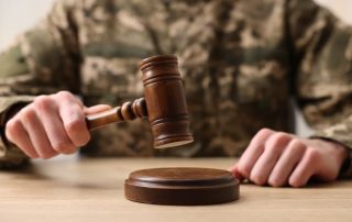 Law concept. Man in military uniform with gavel at wooden table.