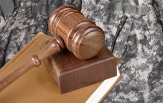 Military law concept: A soldier in uniform stands beside a wooden gavel in a courtroom setting, symbolizing the intersection of military service and legal proceedings.