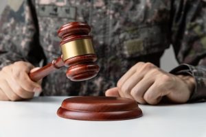 A soldier's hand holding a gavel in a courtroom, symbolizing the concept of military law.