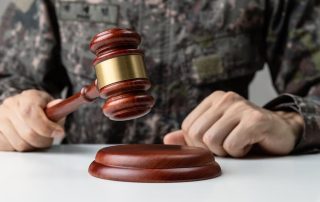 A soldier's hand holding a gavel in a courtroom, symbolizing the concept of military law.
