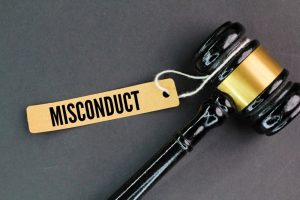 A judge's gravel alongside a paper tag labeled "misconduct," representing the concept of employee or student wrongdoing.