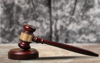 A soldier stands in a courtroom beside a wooden gavel, symbolizing the concept of Military Law.