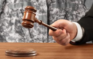 A soldier stands in a courtroom with a wooden gavel, representing the concept of Military Law.