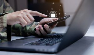 Close-up of a soldier's hand using a smartphone to check authorization for accessing security data, with security and privacy virtual icons displayed, symbolizing military operation control.