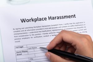 Close-up of a woman's hand filling out a workplace harassment form.