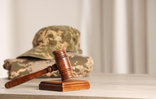 A law concept image featuring a gavel placed beside a military uniform on a wooden table, leaving space for text.